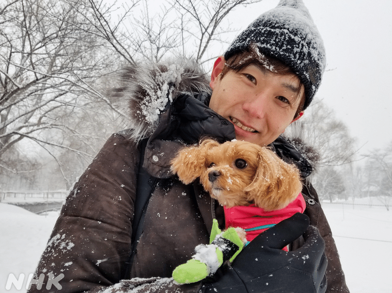 雪の風景のなか、愛犬の茶色い小型犬を上着の中に入れて微笑む瀬田アナ。