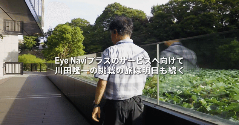 道を歩く川田さんの後ろ姿の画像。画像には、「Eye Naviプラスのサービスへ向けて川田隆一の挑戦の旅は明日も続く」と書かれている。
