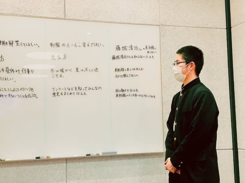 ホワイトボードの前に立つ小松平さんの写真