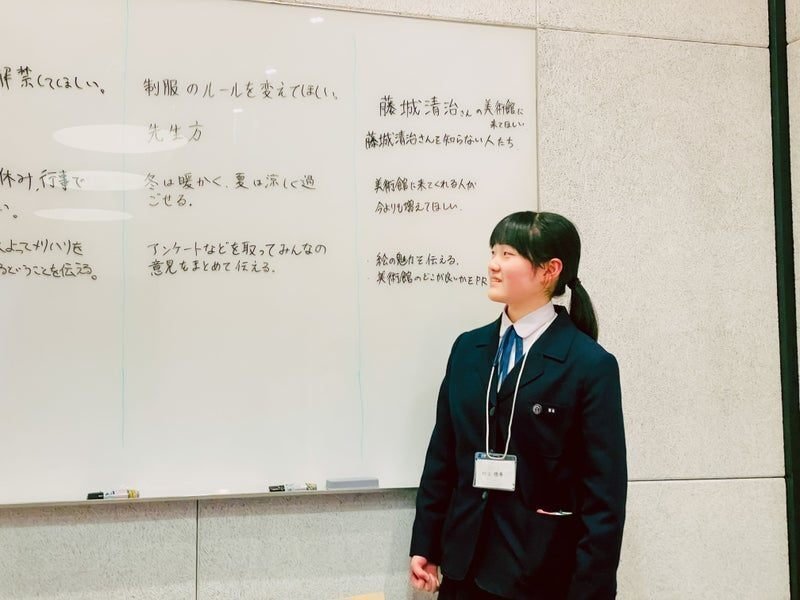 ホワイトボードの前に立つ村上さんの写真