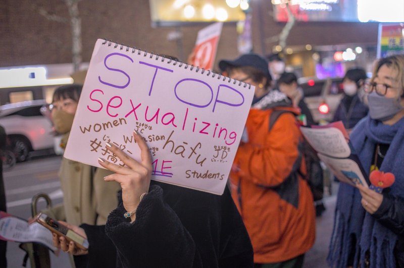 プラカード「STOP sexualizing ME　women　JC　Whasian　hāfu　JD 女子高生　JS　students」
