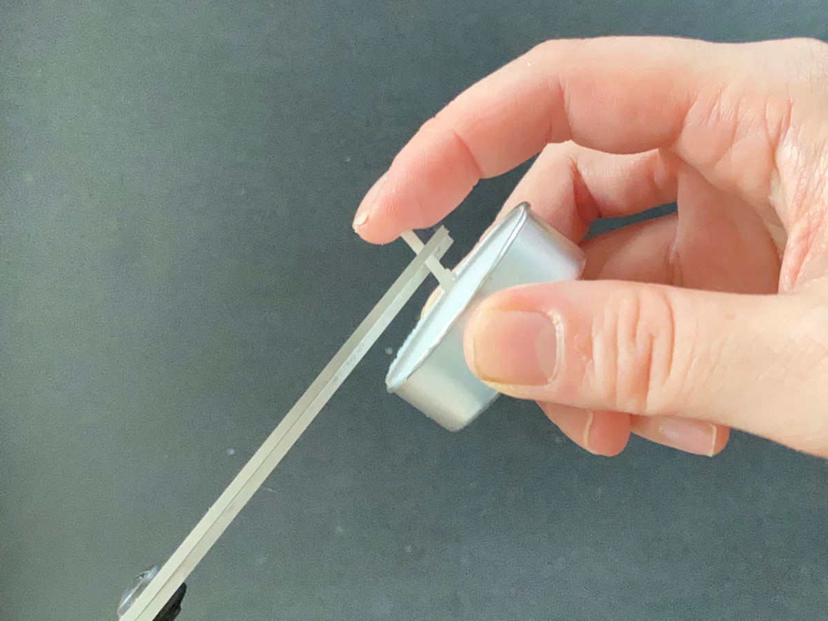 キャンドルの芯を半分以下にハサミで切っている様子。