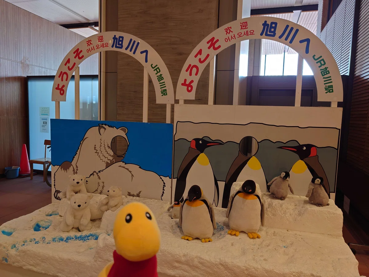 「ようこそ旭川へ」JR旭川駅と書かれている旭川駅改札内の歓迎ボード.シロクマとペンギンのぬいぐるみが並んでいる.