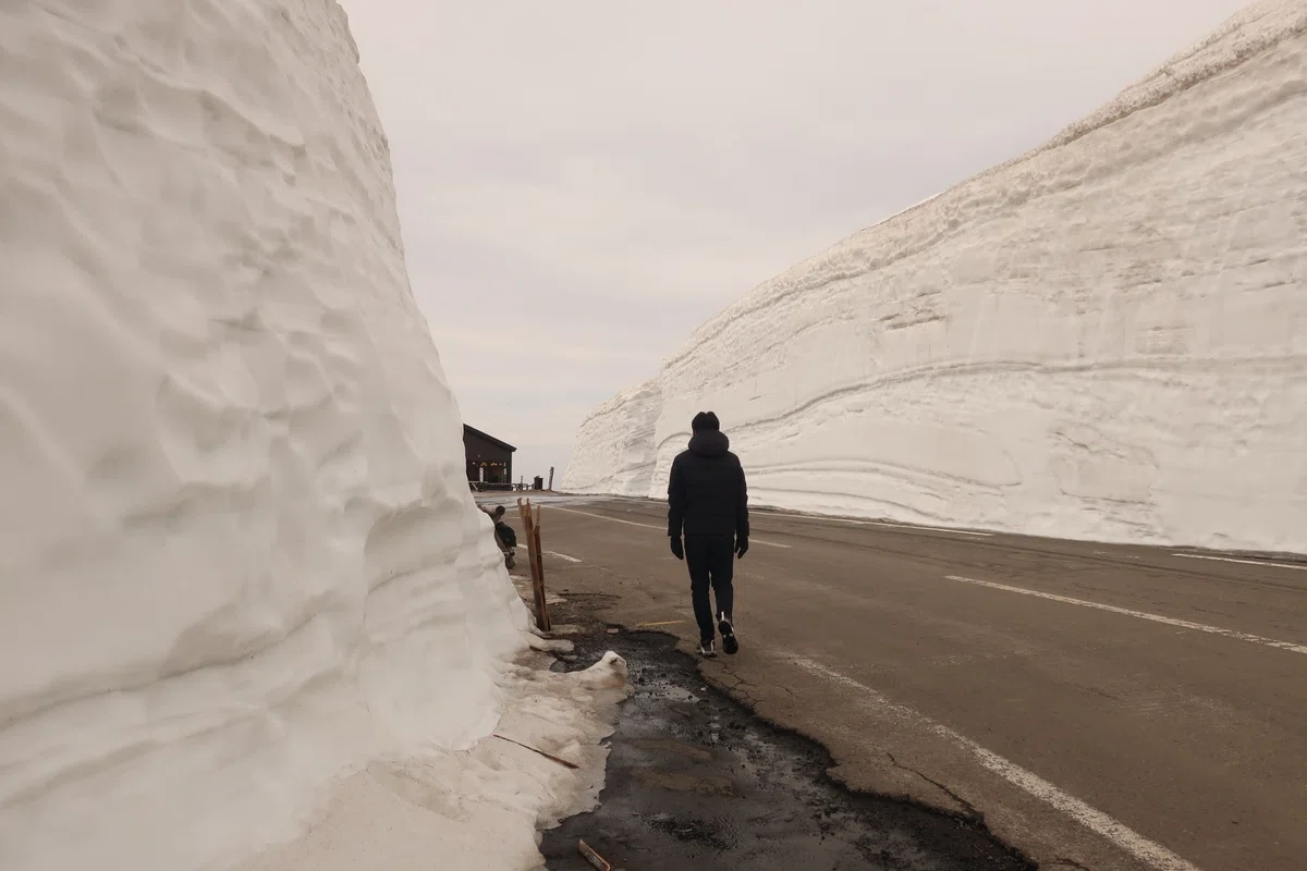 雪の壁の間を歩く夫