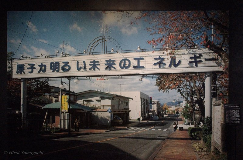 「原子力明るい未来のエネルギー」と書かれた看板が街の中央に掲げられている写真の複写です。