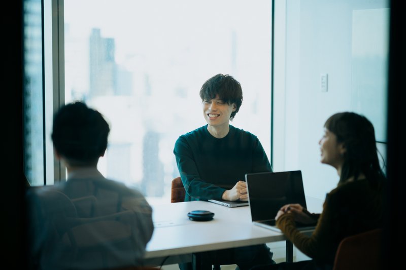 会議室で談笑する社員の写真。浅井さんも写っている
