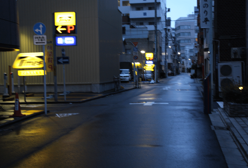 イメージ画像：早朝の路上の風景。街灯が雨上がりの路面に反射している