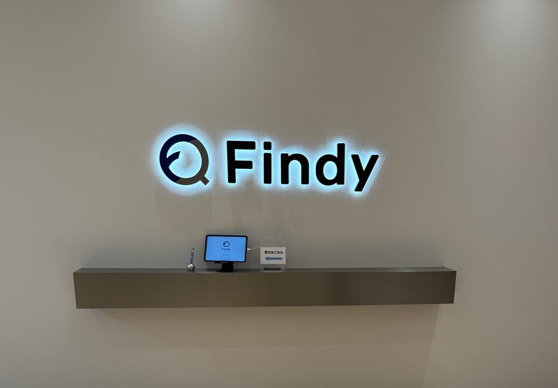 オフィスのエントランスの写真です。Findyと白く光っているロゴが設置されています。