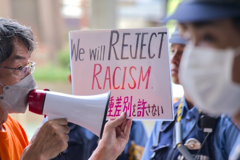プラカード「We will REJECT RACISM. 人種差別を許さない」