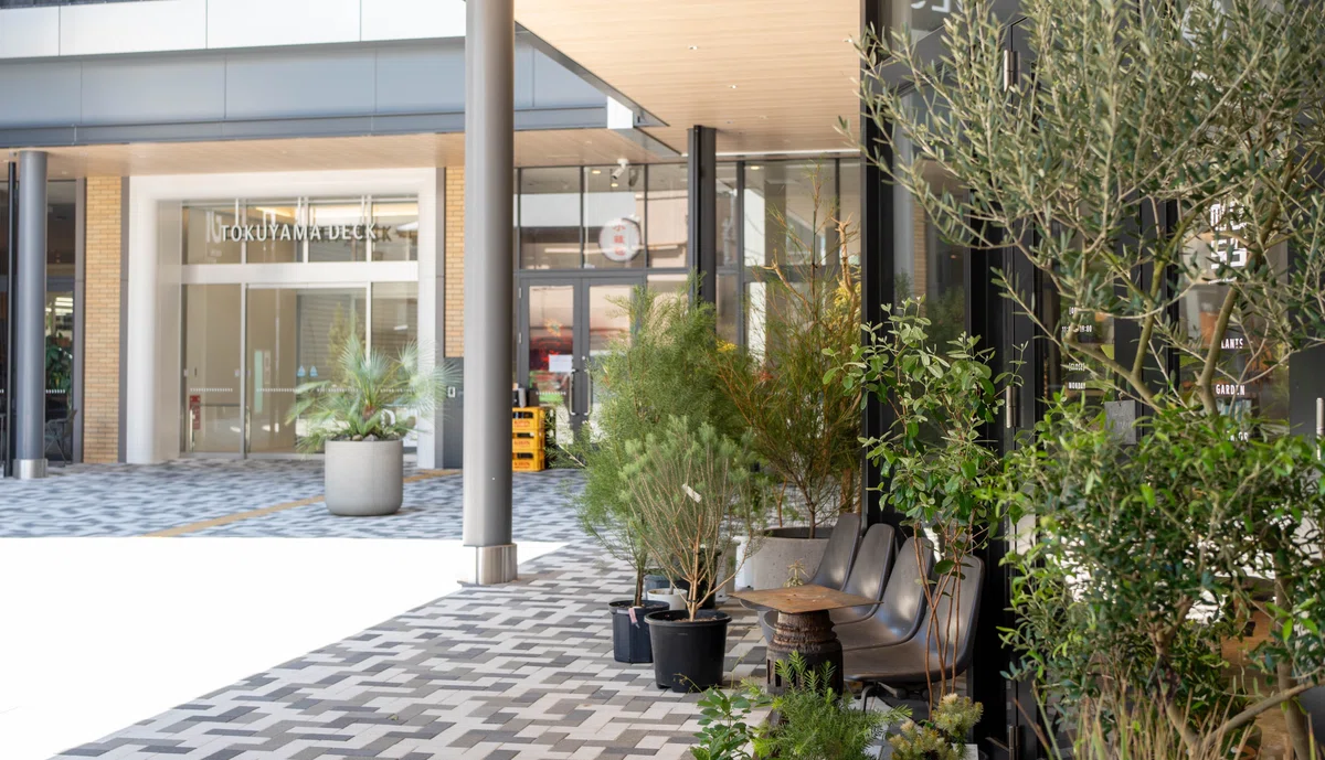 奥にTOKUYAMA DECKの入口、手前に植物が飾られた店舗