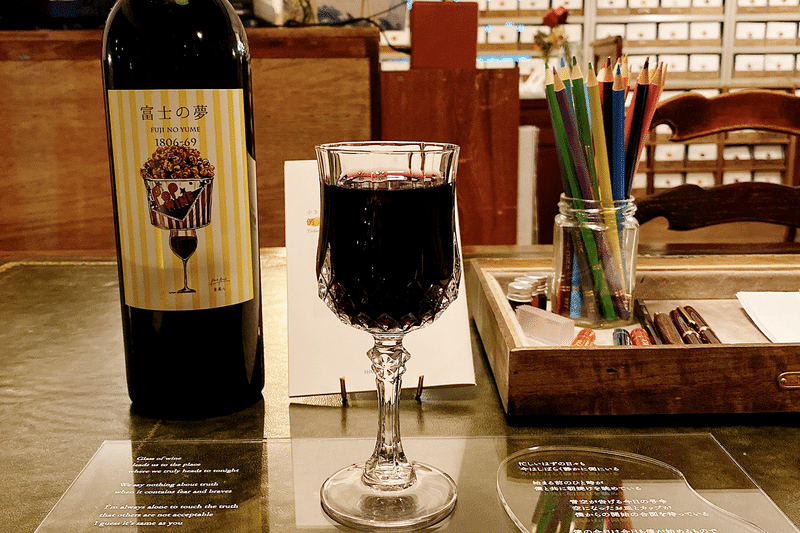 富士の夢というワインボトルとなみなみと注がれたグラス。文机の上にえんぴつ立て、プレートには詩の一節