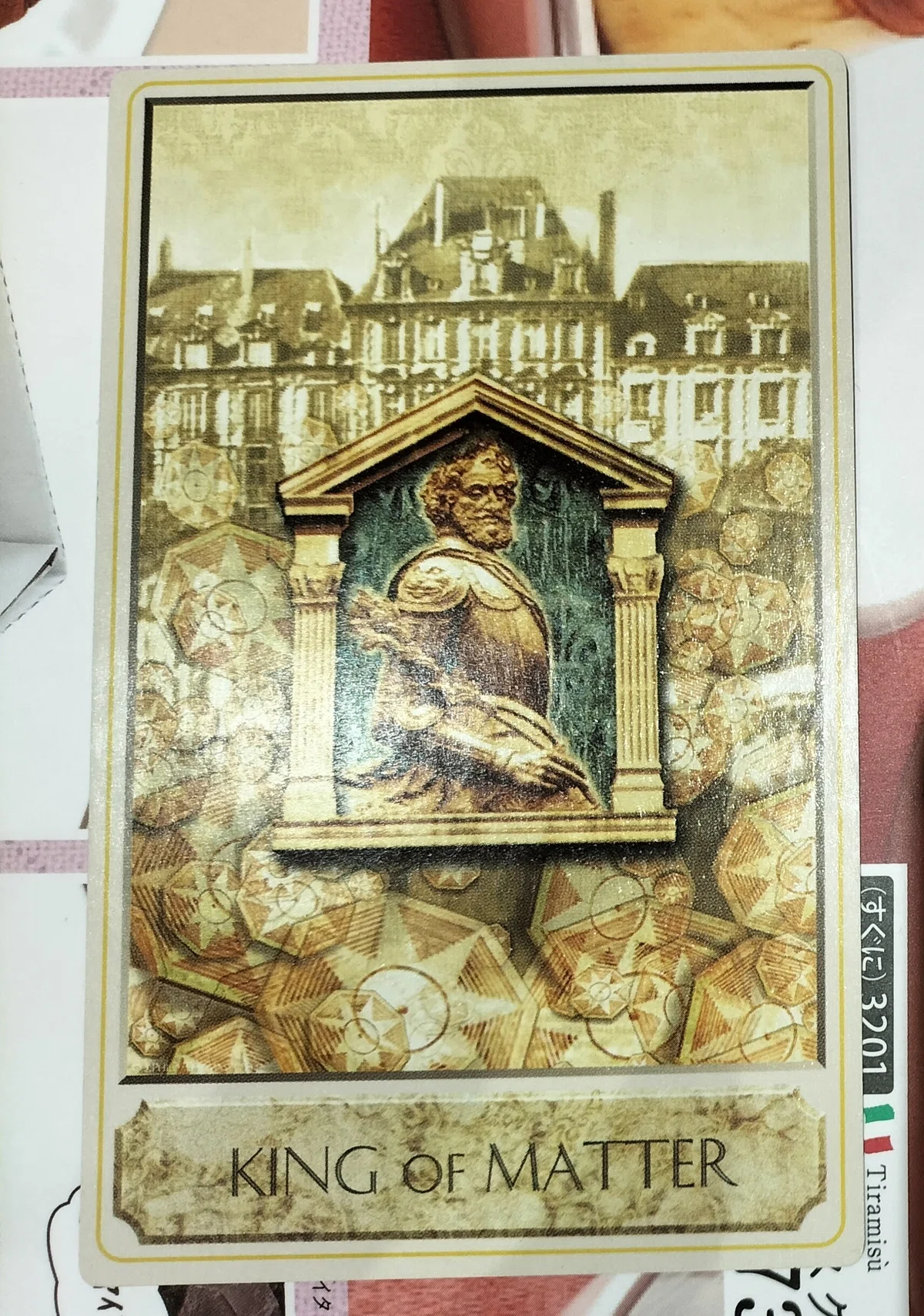 マターのキングというカード。大きな屋敷、金貨、神殿の形のレリーフに甲冑をまとった中年の男性がえがかれている