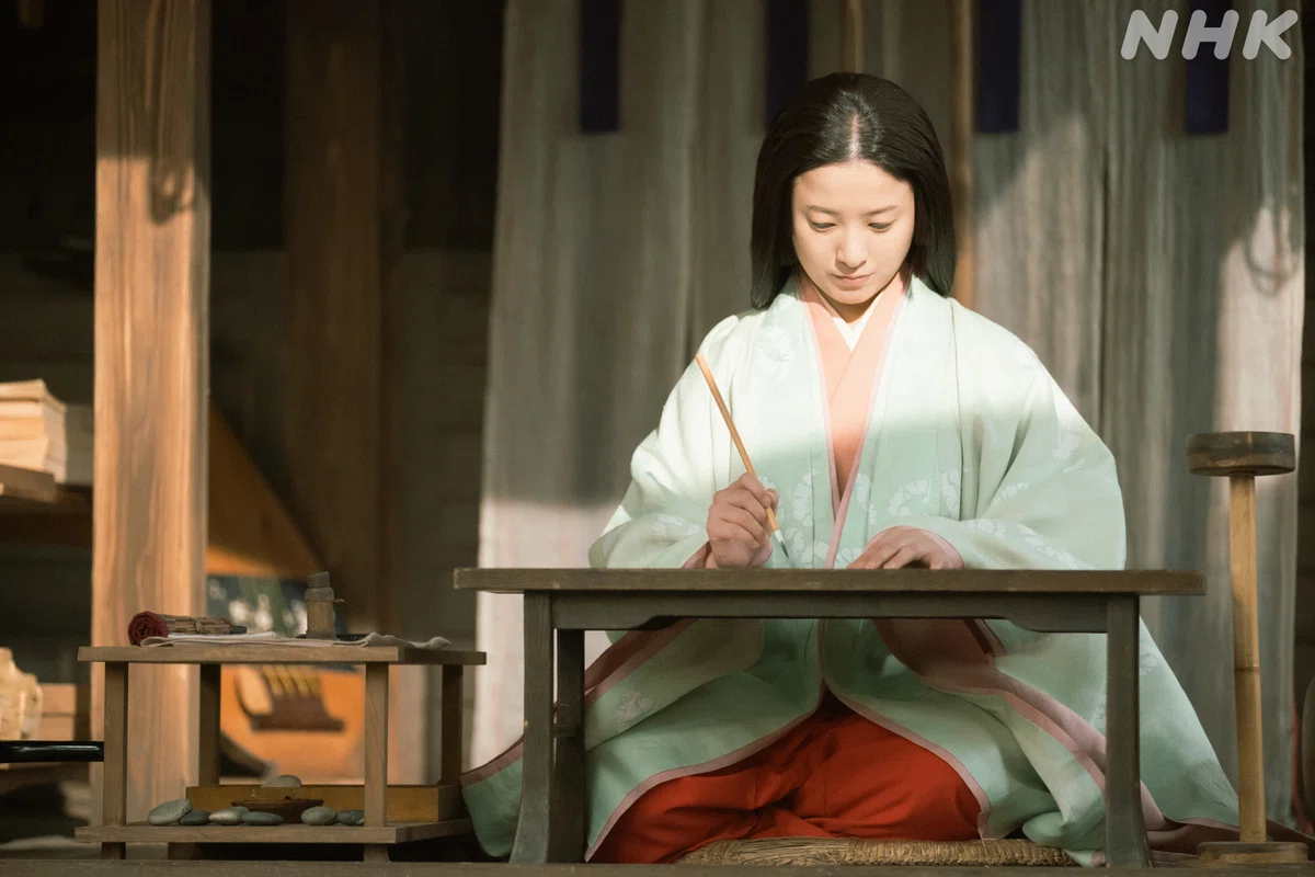 まひろ（吉高由里子さん）が文机に向かい筆を持つようす
