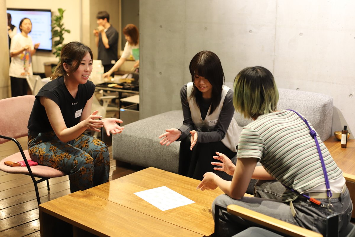 画像:ワールドカフェの様子。3人の女性がテーブルのまわりで談笑している。テーブルの上には一枚の紙が置かれている。
