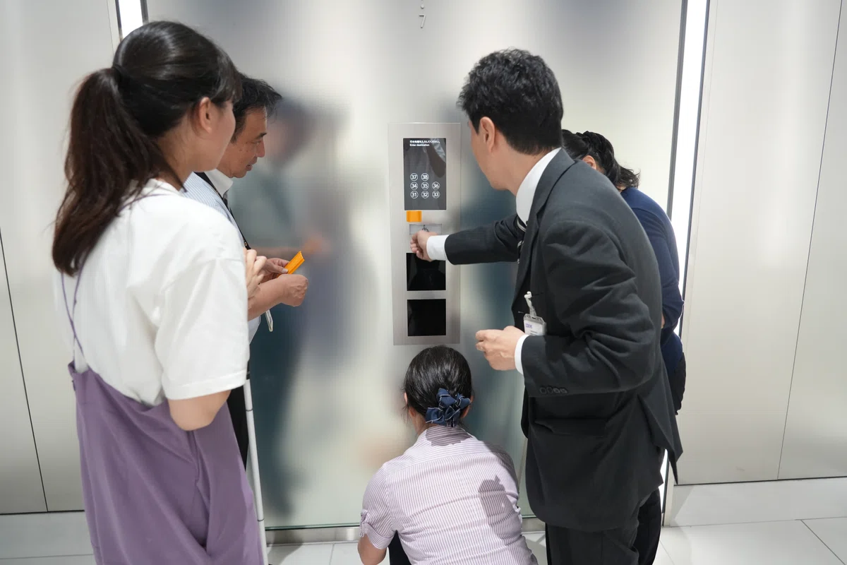 エレベーターの操作パネルに5cm程度にカットしたココテープを貼り付けている写真。