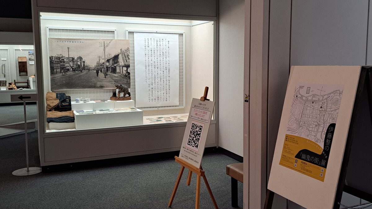 小樽市立博物館本館〈幽鬼の街・小樽とその時代を歩く〉の展示室入口の写真。アットゥシや古写真、展覧会のポスターがうつっている。