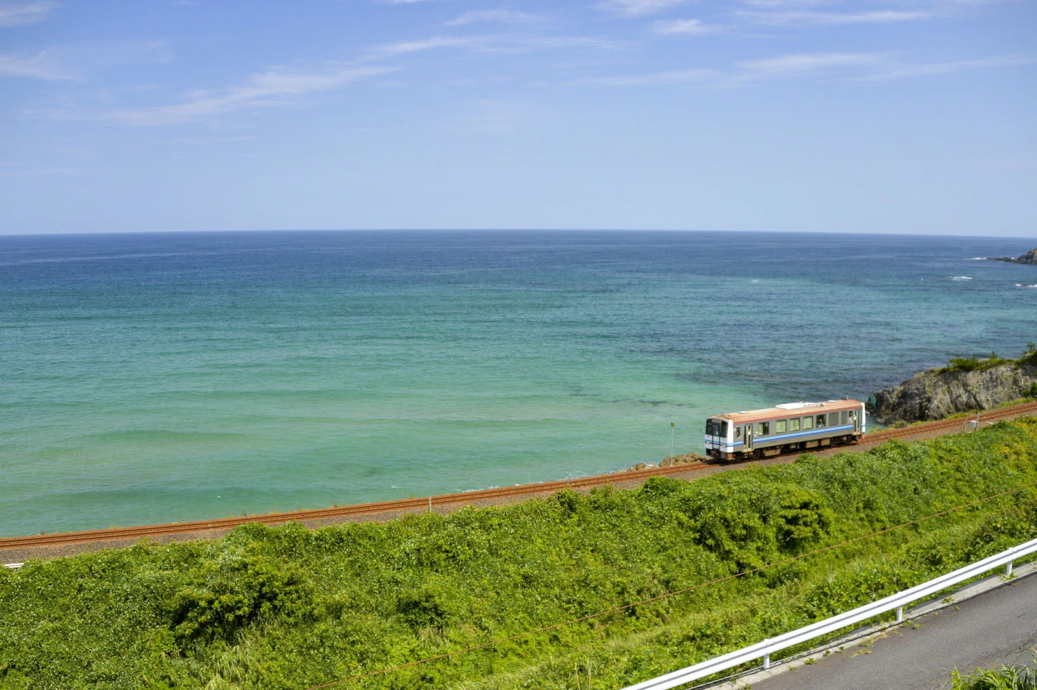 島根の美しい風景をただ礼賛したい。きれいな海を背景に、列車が行っ