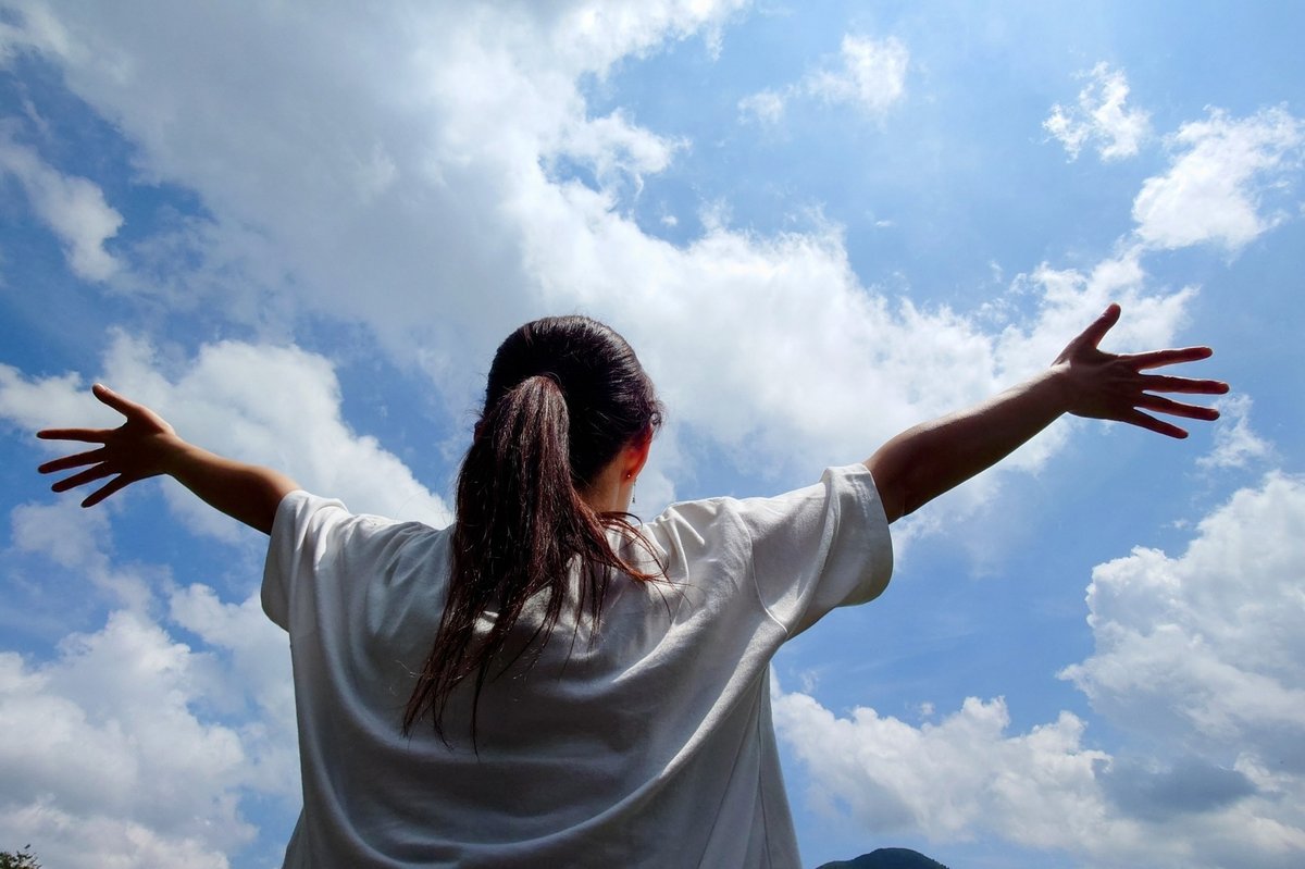 大空に手を広げる女性