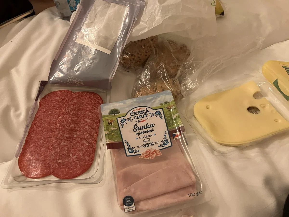 サラミ、ハム、チーズ、パンがベッドの上に載っている