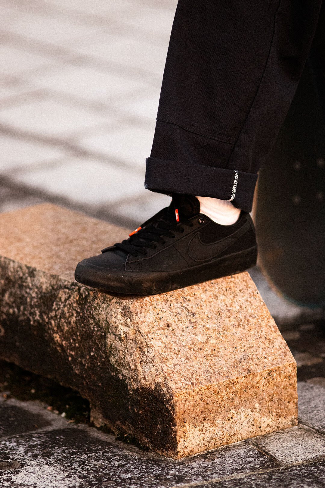 オレンジの夕日に照らされるオールブラックのNIKE SBシューズ