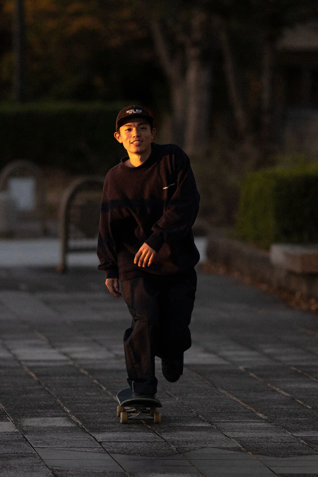 オレンジの夕日に照らされるオールブラックのNIKE SBシューズ。｜HI5