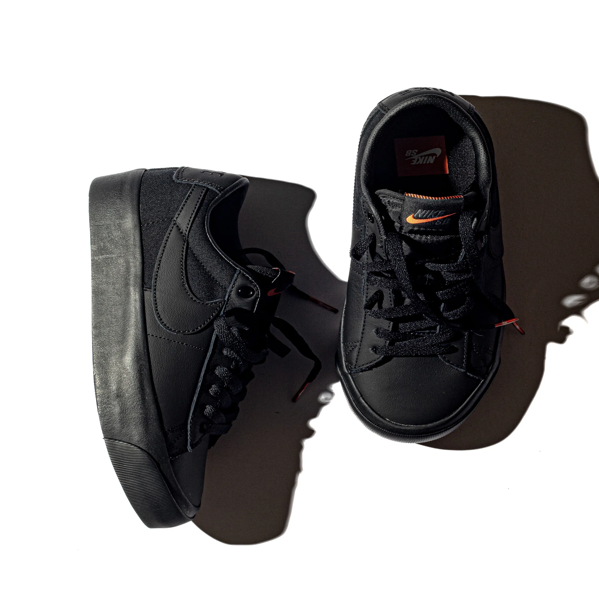 オレンジの夕日に照らされるオールブラックのNIKE SBシューズ 