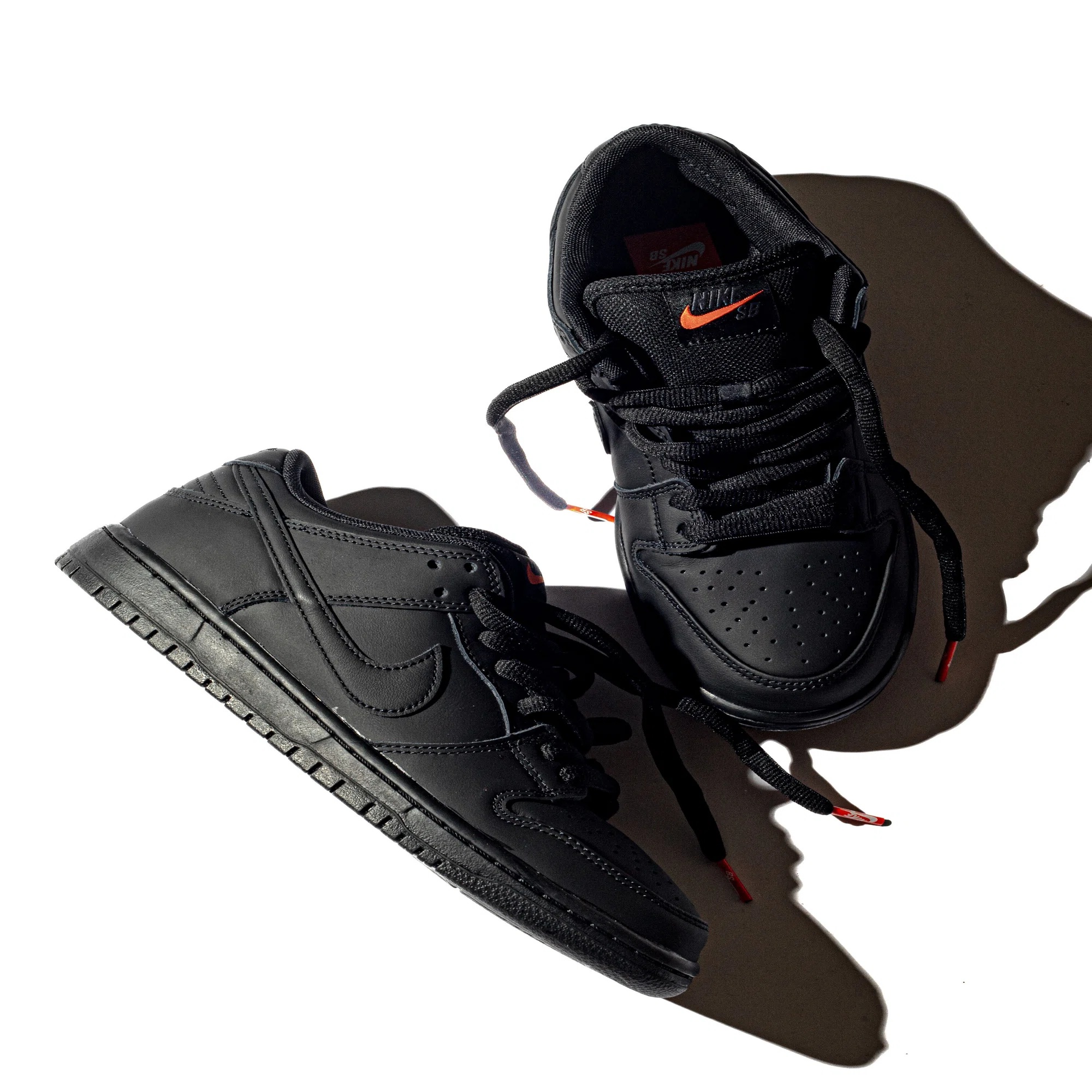 オレンジの夕日に照らされるオールブラックのNIKE SBシューズ 