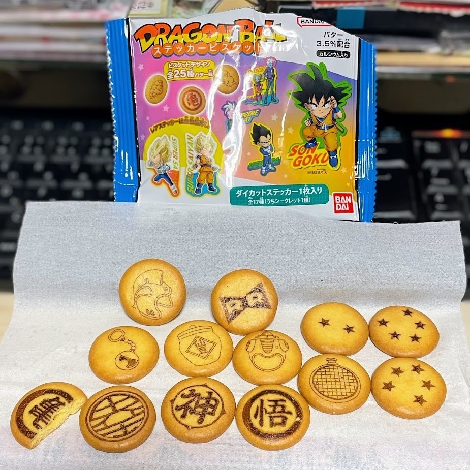 ドラゴンボール　ステッカービスケット　パッケージと中身　円盤状の小さいビスケットにドラゴンボールに登場するモチーフがプリントされている　星、ドラゴンレーダー、レッドリボン軍マーク、チチのヘルメット、仙豆の壷、ポタラ、「悟」マーク、神マーク、界王マーク、亀マーク