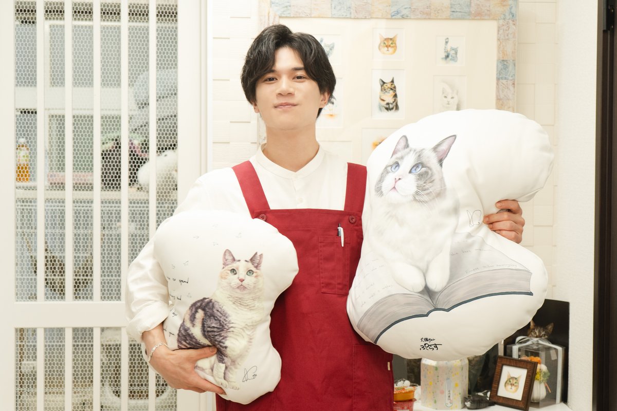 「犬猫サロンぷらす」さんのエプロンを着用し、オリジナルグッズのクッションを持つ蒼木さん（撮影＝上野留加）