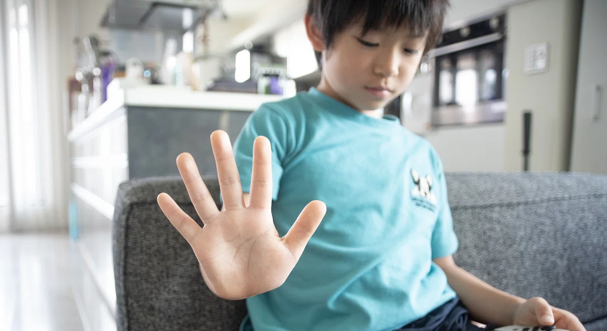 手のひらを広げてこちらに向けている男の子。