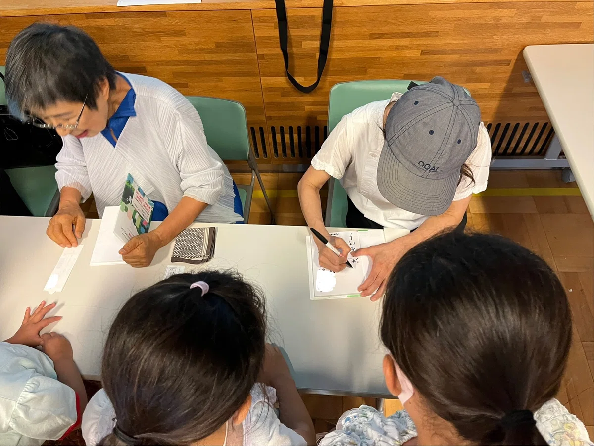 購入した書籍に池田香代子さんとイラストの山内マスミさんにサインを書いてもらっている写真
