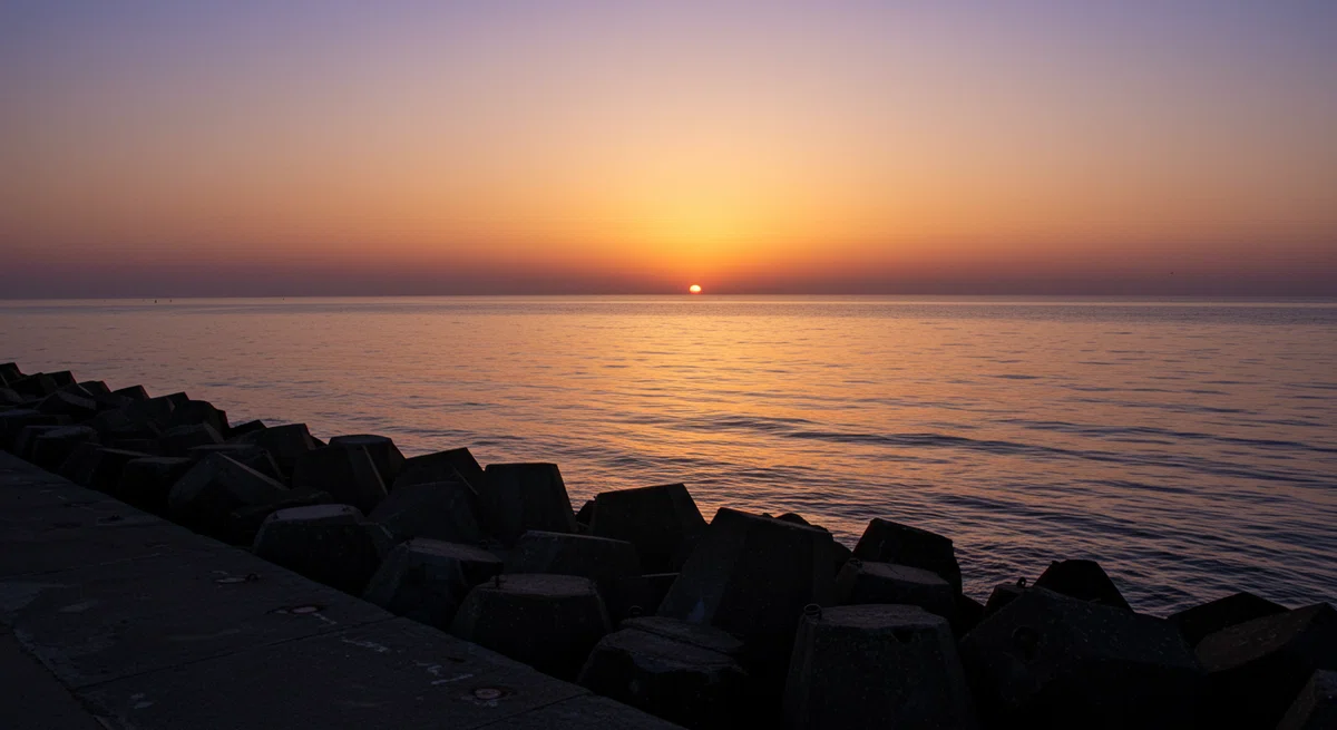 静かな堤防から見た、夕暮れの海の風景。