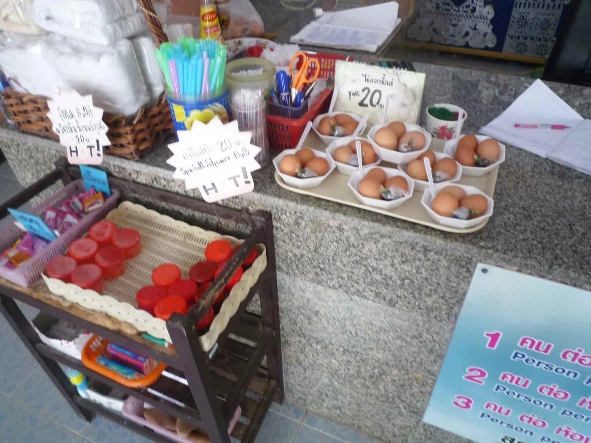 受付カウンターの上に温泉卵のトレイが並び、横にタオルや石けん、小物が置かれている。値札が見える。