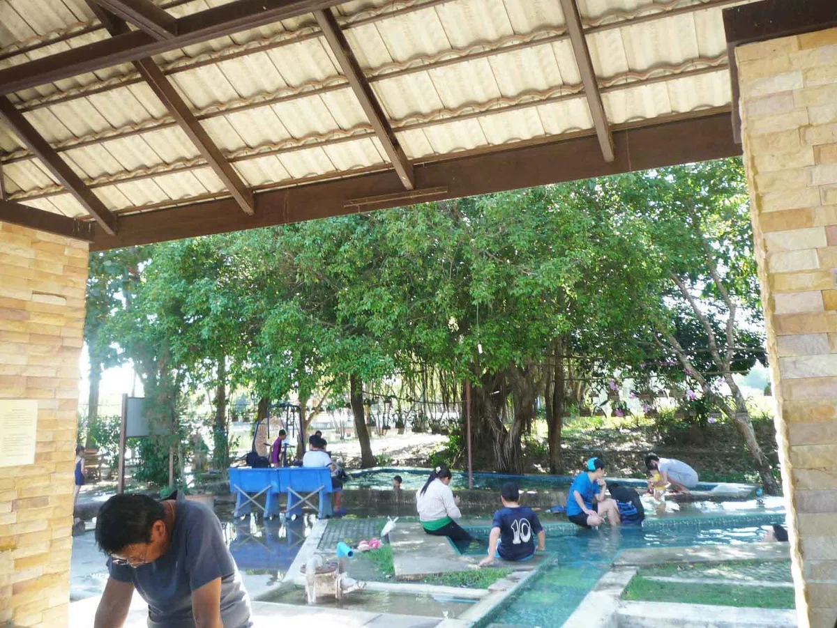 屋根下の足湯全景。ベンチに人々が並び、湯気が薄く流れている。
