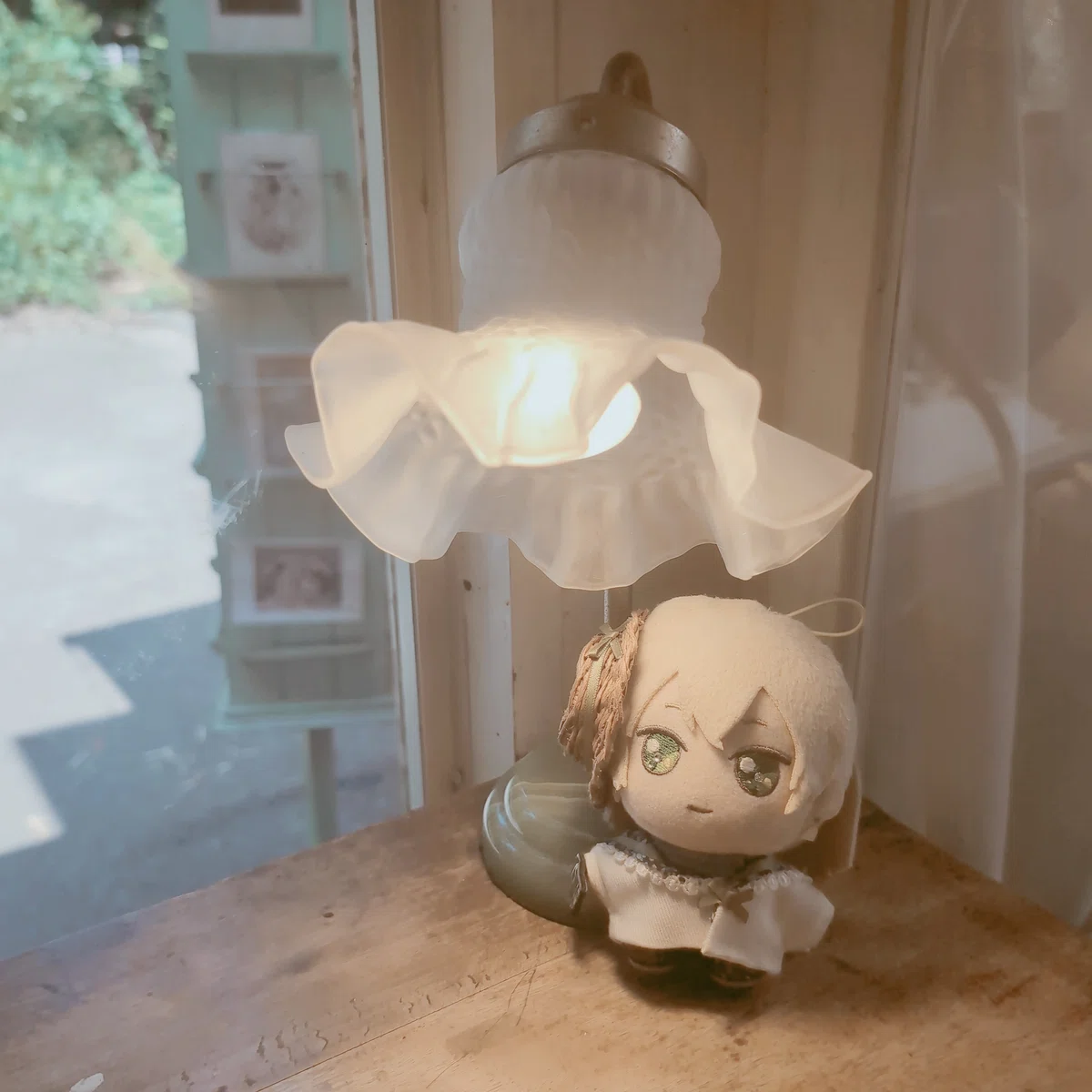 カフェのテーブル。チューリップ型のスタンドライトが置かれ、その足元に魔法使いの約束のルチルのぬいぐるみが佇んでいる。