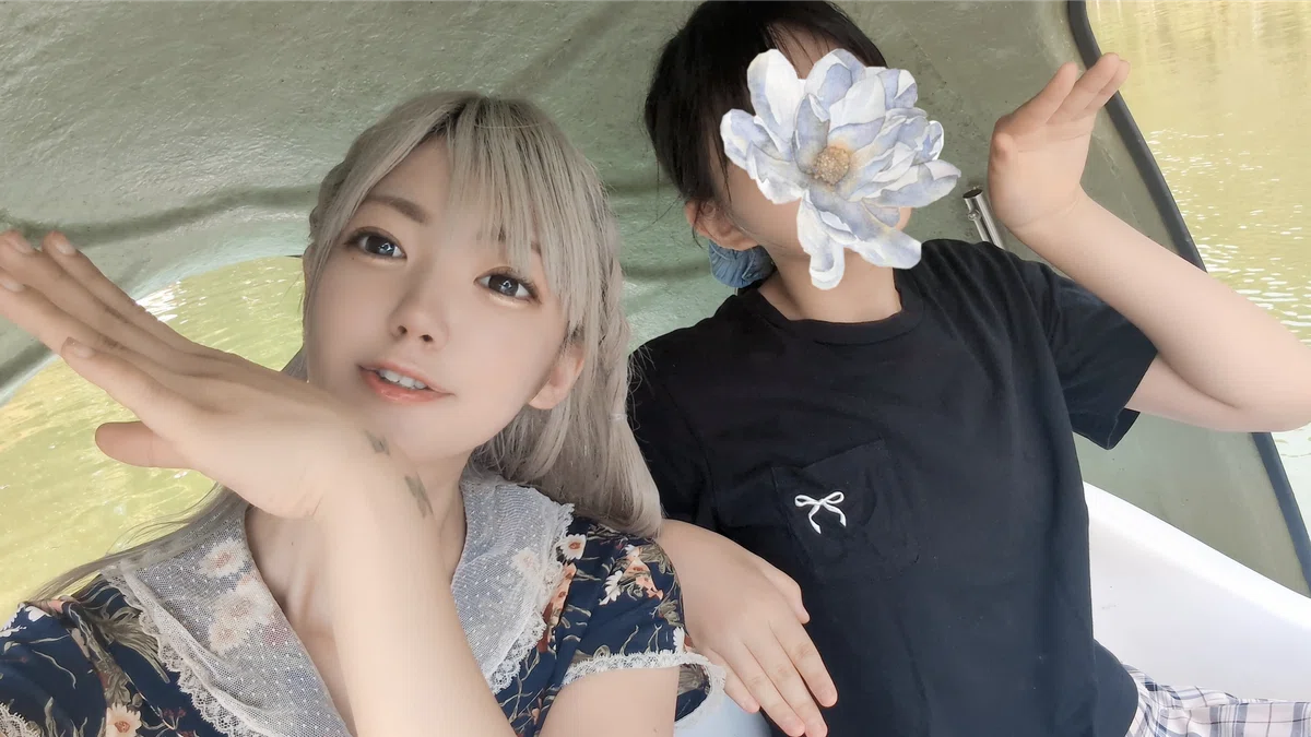 ボートの中でポーズを取る二人の人物。手のひらをくちばしのような形に曲げている。