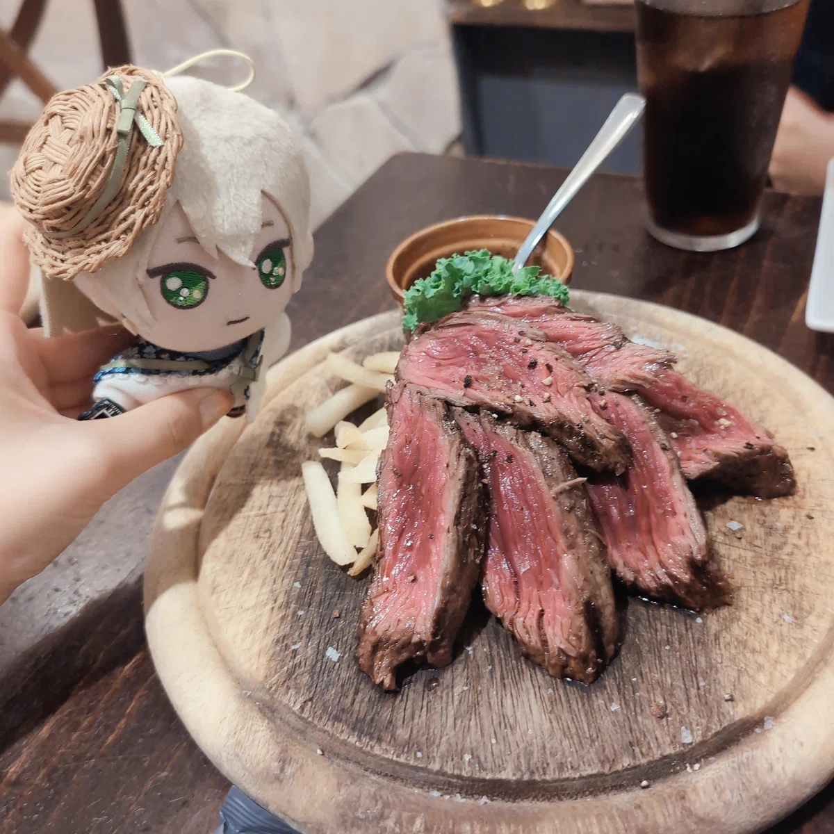カフェのテーブル。赤身の肉を焼いた料理が木の皿に乗っている