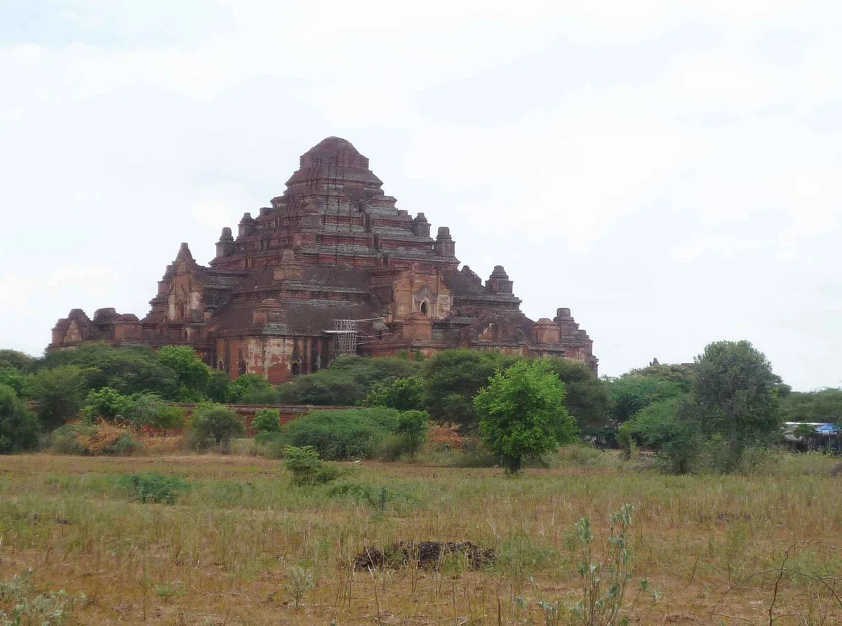 草地の先にそびえる段状の赤レンガ建築、ダマヤンジー寺院の外観