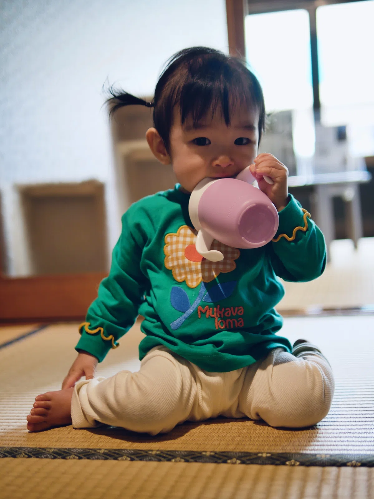 お気に入りのマグを加えている赤ちゃん