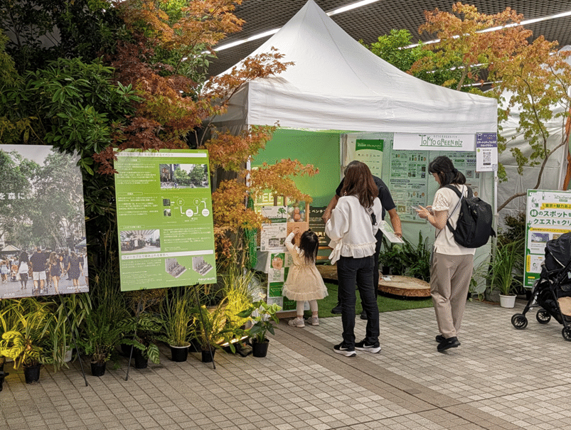 木々や植物(緑や赤など)に囲まれた東京グリーンビズのブースの様子。