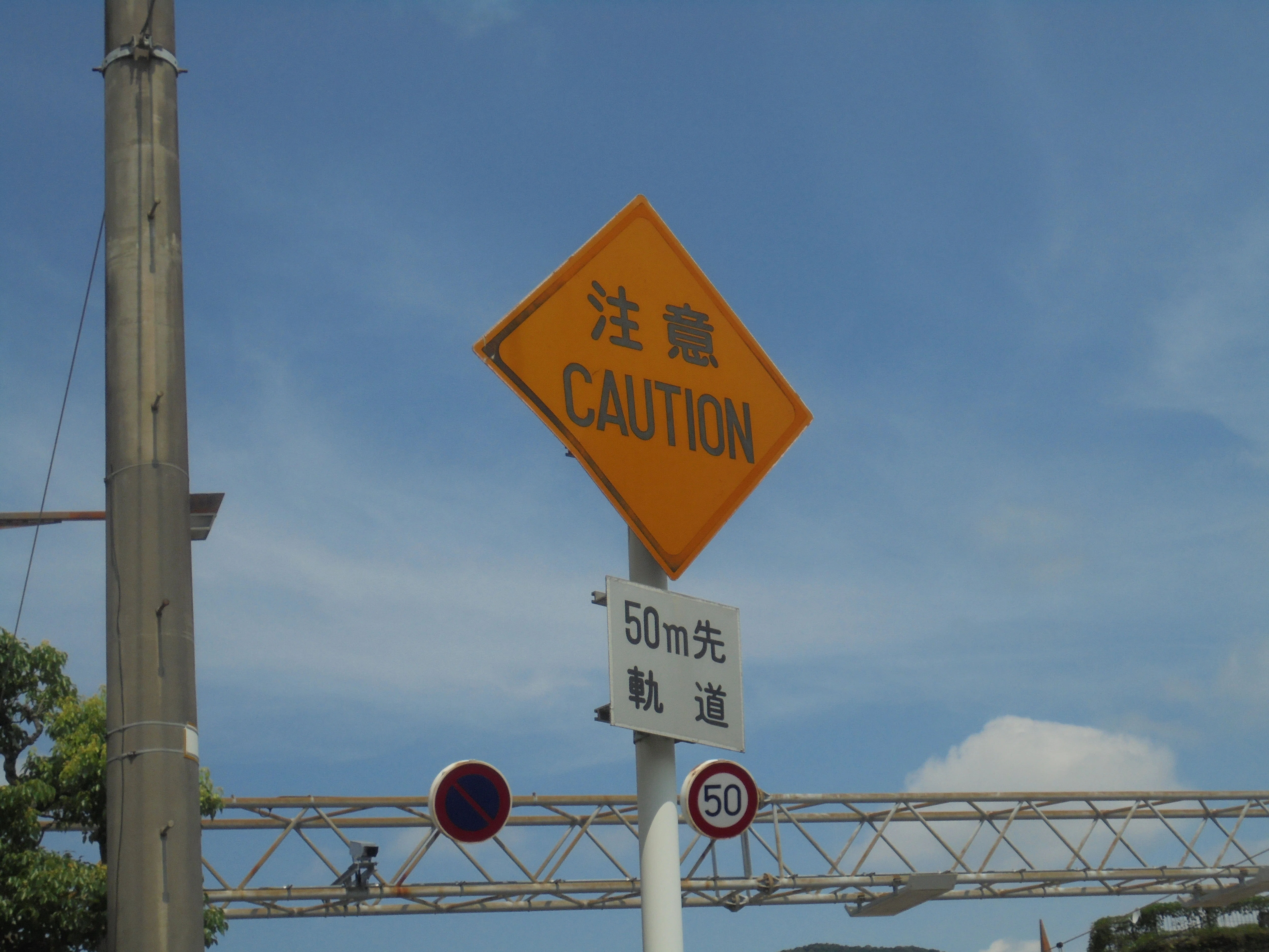 長崎県長崎市蛍茶屋電停付近の「上」信号機と「注意 CAUTION」標識