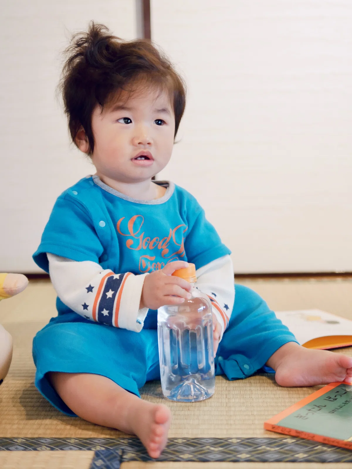 1歳の男の子が水の入ったペットボトルを持ち、どう遊ぼうか思案しているところ