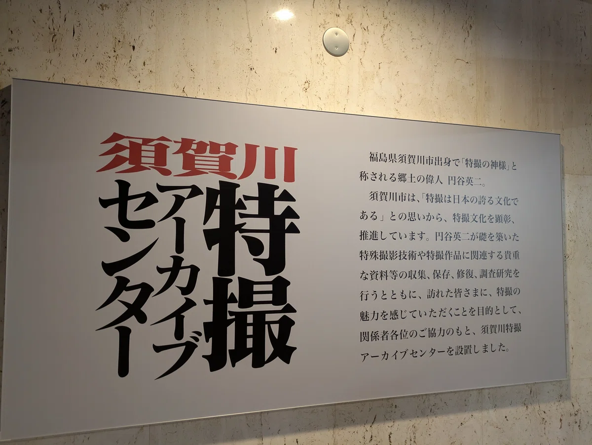 「須賀川特撮アーカイブセンター」エントランス看板。「福島県須賀川市出身で「特撮の神様」と 称される郷土の偉人 円谷英 須賀川市は、「特撮は日本の誇る文化で ある」との思いから、特撮文化を顕彰、 推進しています。円谷英二が礎を築いた 特殊撮影技術や特撮作品に関連する貴重 な資料等の収集、保存、修復、調査研究を 行うとともに、訪れた皆さまに、特撮の 魅力を感じていただくことを目的として、 関係者各位のご協力のもと、須賀川特撮 アーカイブセンターを設置しました。」