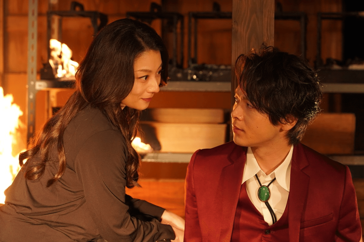 炎の前で向き合う男女の緊張感あるシーン