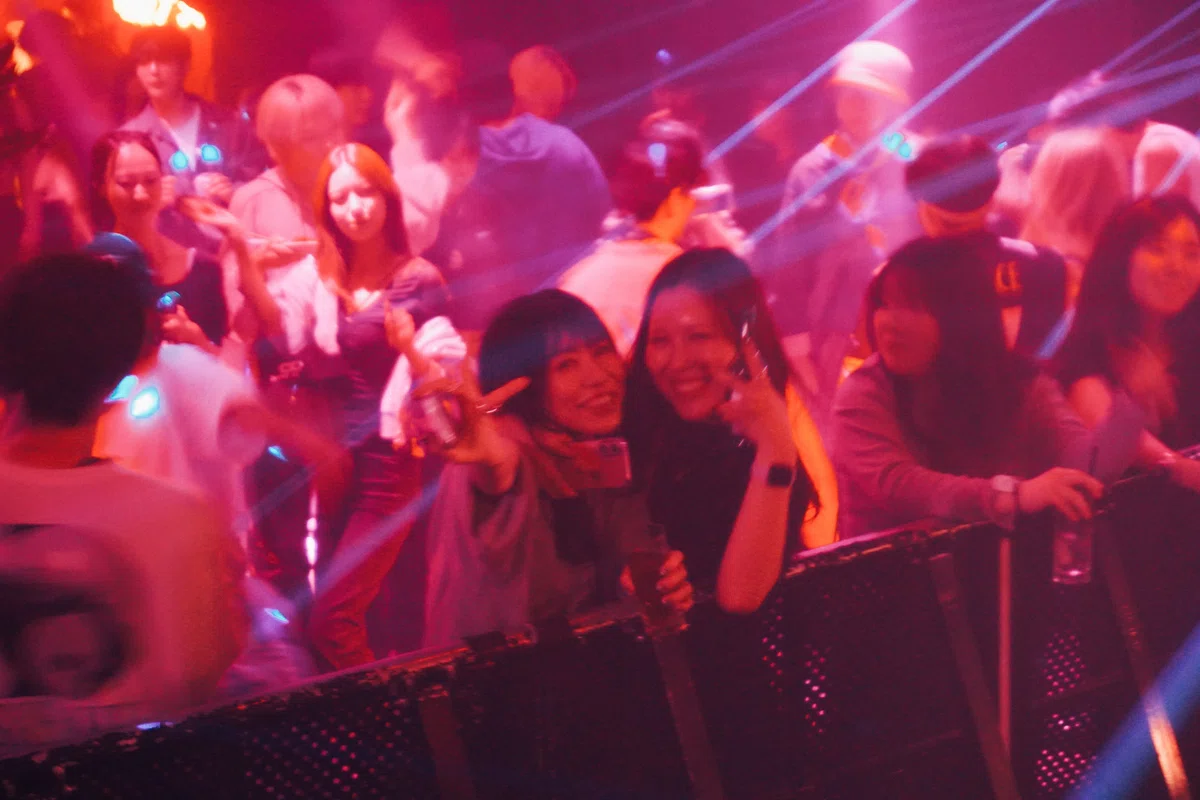 ピンクとブルーのレーザーライトが交差するダンスフロア。観客がスマホを掲げて盛り上がり、笑顔があふれる瞬間。
The dance floor glows in pink and blue laser lights as guests smile, dance, and capture the moment with their phones.