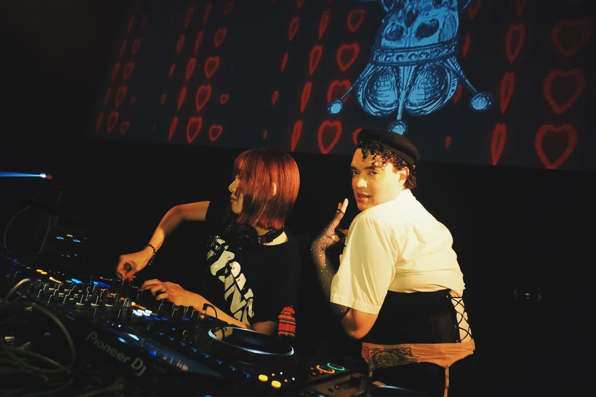 DJブースでパフォーマンスするDJ CHIKA。赤いハートが流れるビジュアルを背に、NESTALの夜を象徴する1シーン。
DJ CHIKA at the DJ booth with red heart visuals in the background — a defining moment of the NESTAL night at WOMB.