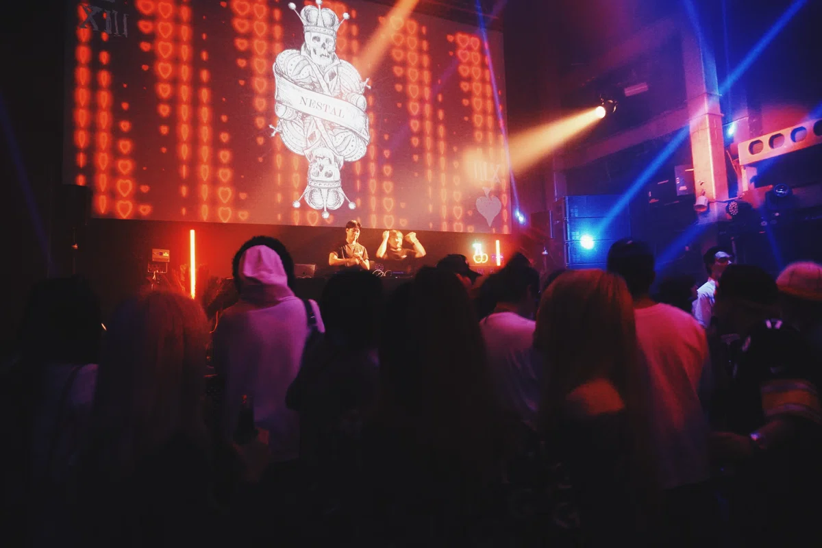 渋谷WOMBのメインフロアで、レーザーライトが交差する中DJがプレイ。観客が音に合わせて踊り、NESTALの熱気が広がる。
The main floor of WOMB Shibuya glows with laser lights as the DJ performs, capturing the vibrant energy of the NESTAL K-POP club night.