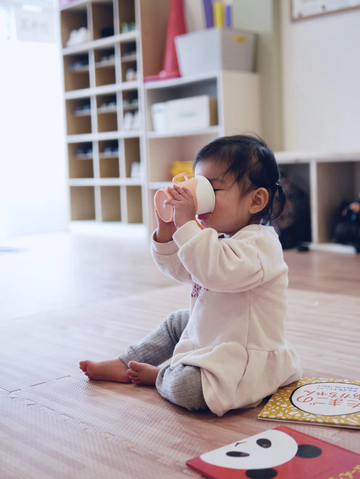 一人で座ってコップのみをしている1歳の女の子