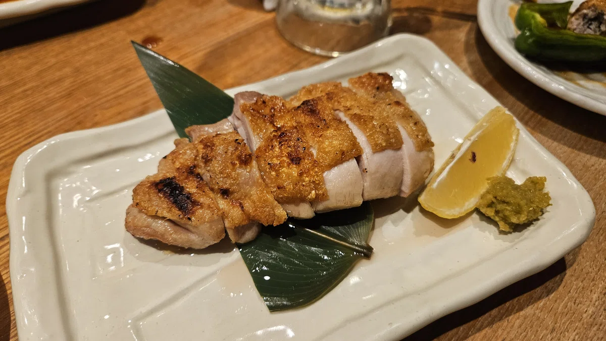 皮目がこんがり焼かれた大山鶏のもも肉。ジューシーな焼き鳥のアップ写真。