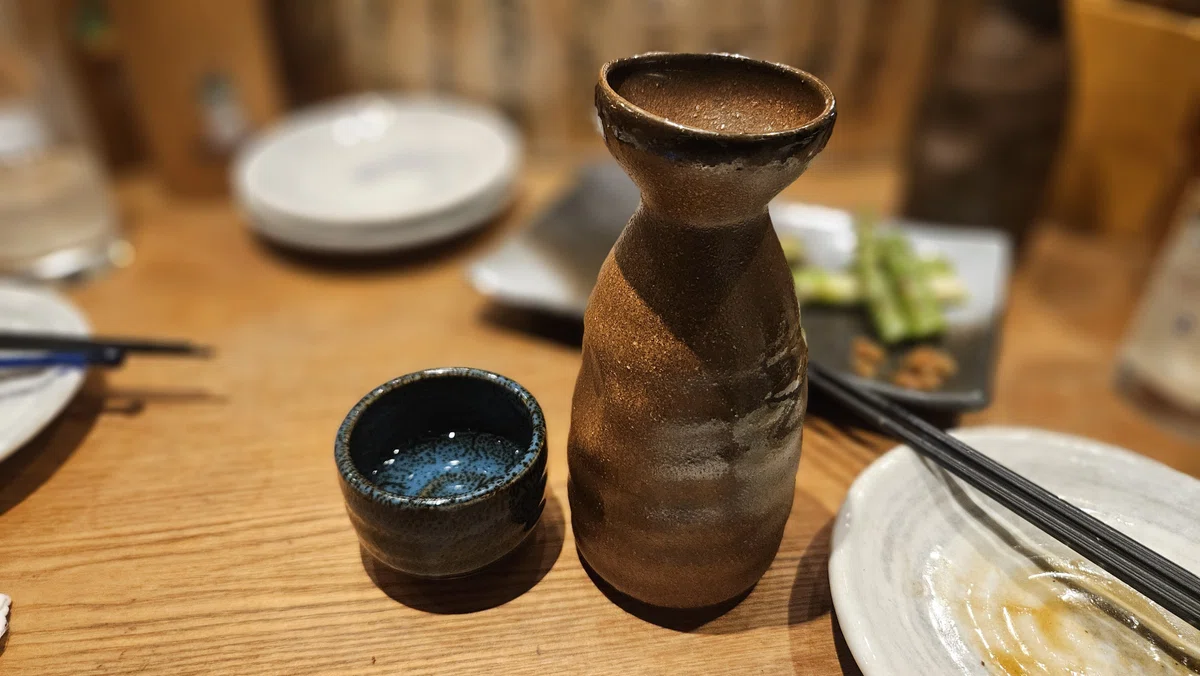 居酒屋のテーブルに置かれた徳利とぐい呑み。日本酒を楽しむ食卓の風景。